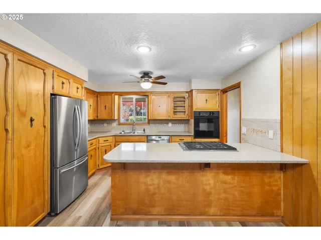 a large kitchen with stainless steel appliances granite countertop a refrigerator and a sink