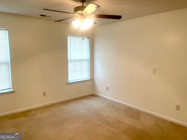 an empty room with a window and a fan