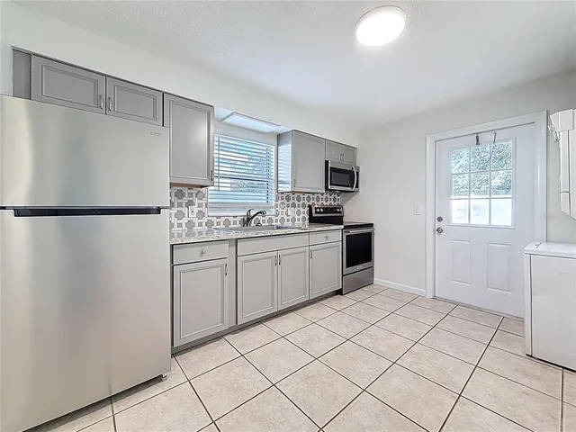 a kitchen with stainless steel appliances a refrigerator sink and microwave