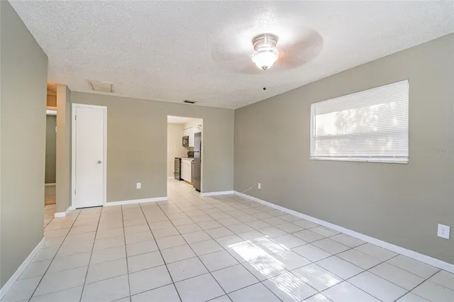 a view of an empty room with window and chandelier fan