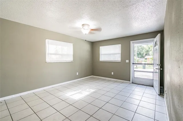 a view of an empty room with window and cabinet area