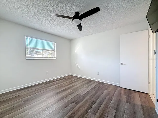 an empty room with wooden floor cabinet and windows