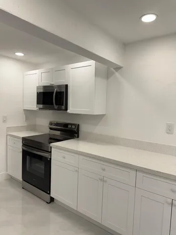 a kitchen with granite countertop white cabinets and stainless steel appliances