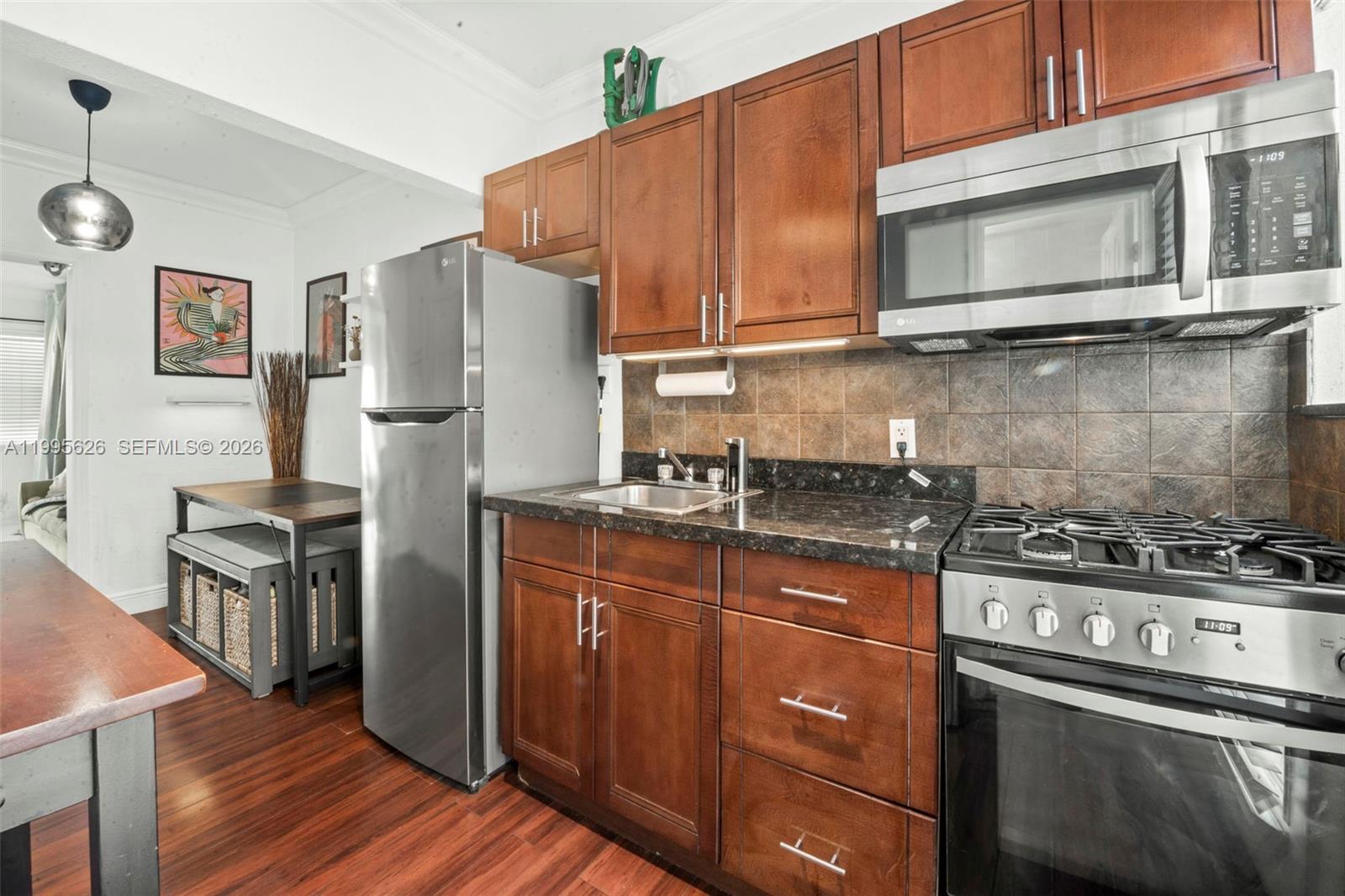 a kitchen with stainless steel appliances granite countertop a stove top oven a refrigerator and a microwave