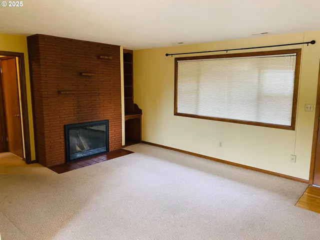 a view of an empty room with a fireplace and a window
