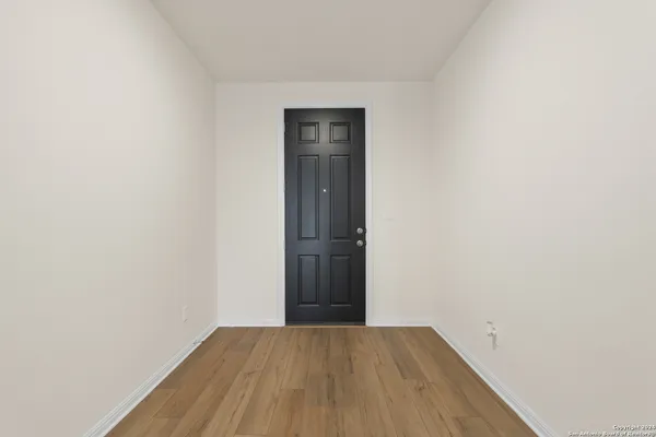 a view of an empty room with wooden floor and closet