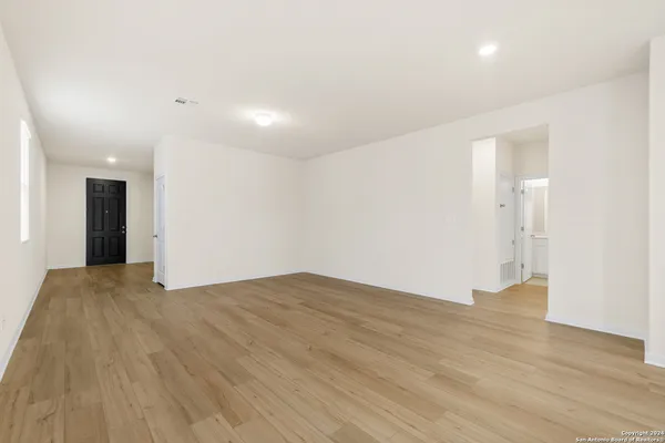 a view of an empty room with wooden floor and closet