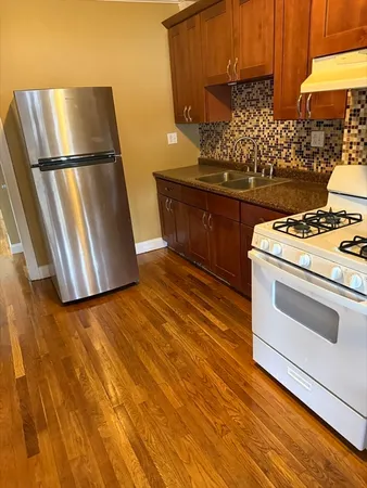 a kitchen with wooden floor and white stainless steel appliances