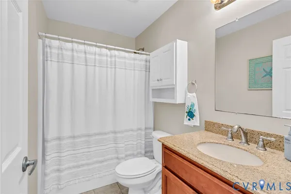 a bathroom with a granite countertop sink toilet a mirror and shower curtain