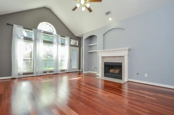 wooden floor fireplace and windows in an empty room