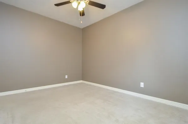 an empty room with a chandelier fan and a ceiling fan