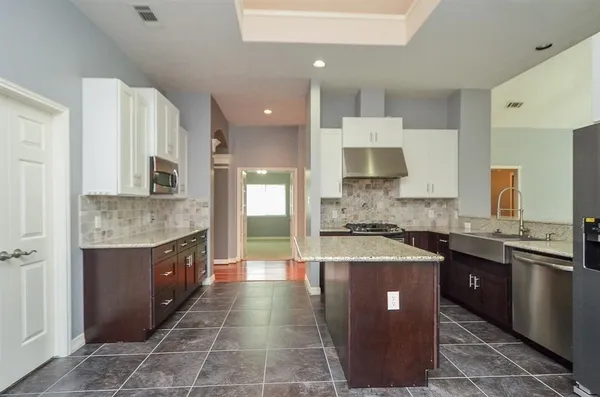 a kitchen with granite countertop a sink a counter top space and cabinets