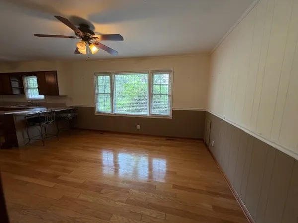 a view of an empty room with window and wooden floor