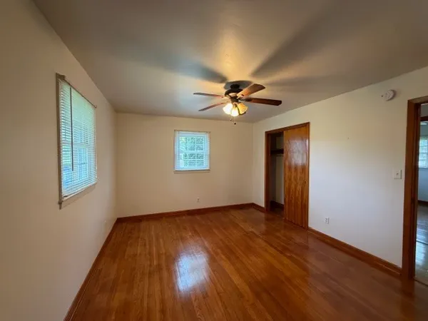 a view of an empty room with wooden floor and a window