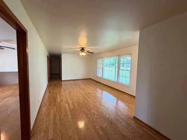 a view of empty room with wooden floor and fan