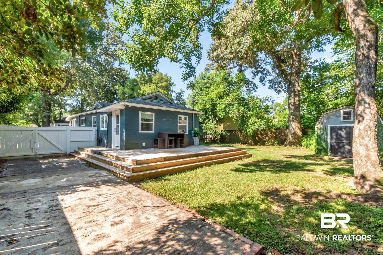 18 Princess Anne Road Mobile, AL 36608 - Photo 38 of 41 Back of property with a storage unit, a gate, a wooden deck, and view of scattered trees