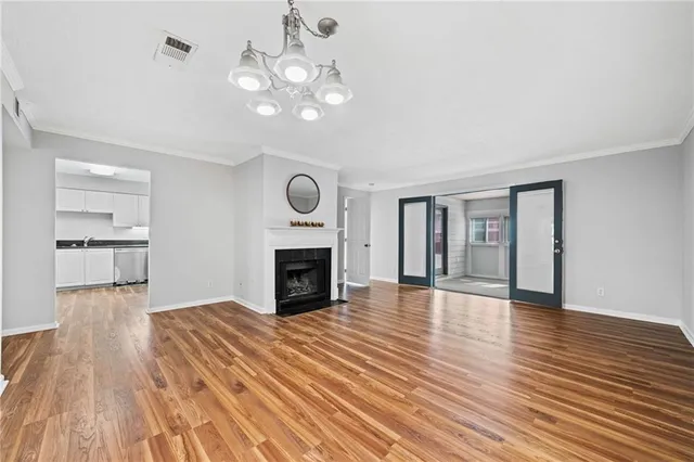 a view of a livingroom with wooden floor and a kitchen