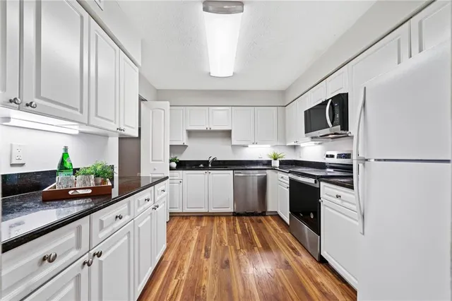 a kitchen with granite countertop a stove top oven a sink dishwasher and a refrigerator