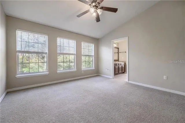 an empty room with chandelier fan and windows