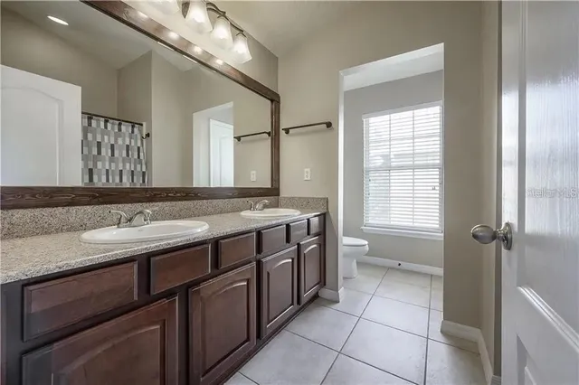 a bathroom with a granite countertop sink a toilet and a large mirror