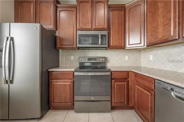 a kitchen with stainless steel appliances granite countertop a refrigerator stove and cabinets