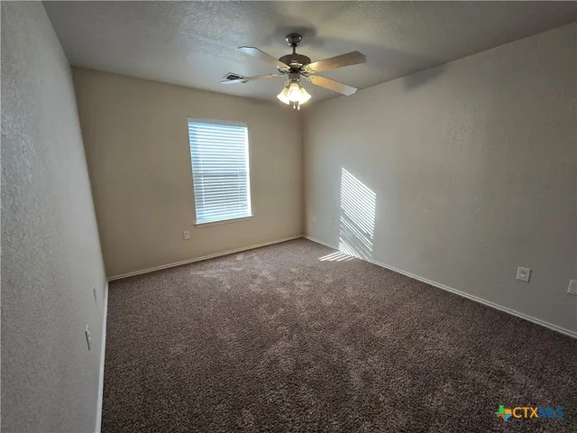 an empty room with windows and chandelier fan