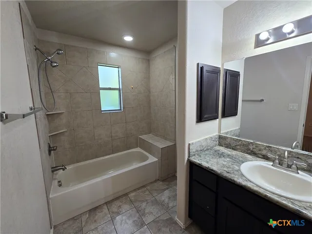 a bathroom with a granite countertop sink a mirror toilet and bathtub
