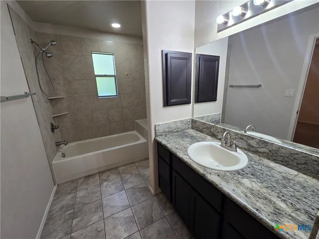 a bathroom with a granite countertop bathtub sink vanity and mirror