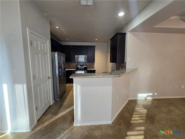 a kitchen with stainless steel appliances a refrigerator and a stove top oven