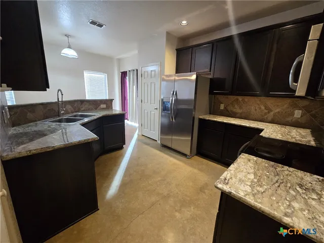 a kitchen with stainless steel appliances granite countertop a sink stove and refrigerator