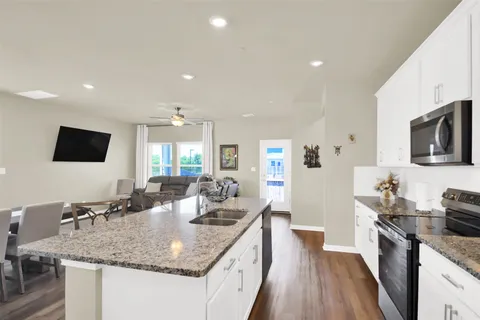 a kitchen with granite countertop a sink and a stove top oven with wooden floor