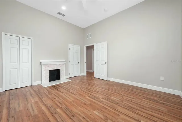 a view of empty room with wooden floor and fireplace
