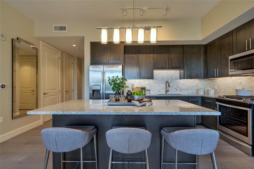 4719 Cole Avenue, Unit 358 Dallas, TX 75205 - Photo 6 of 35 a kitchen with stainless steel appliances kitchen island a table chairs in it and wooden floors
