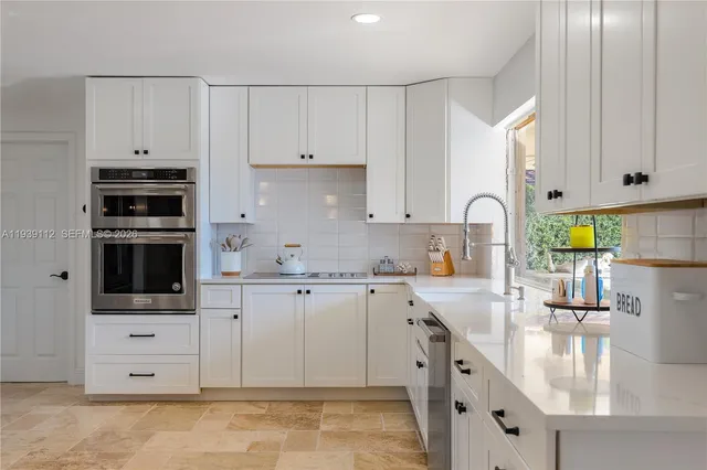 a view of a kitchen with kitchen island a counter top space a sink and stainless steel appliances