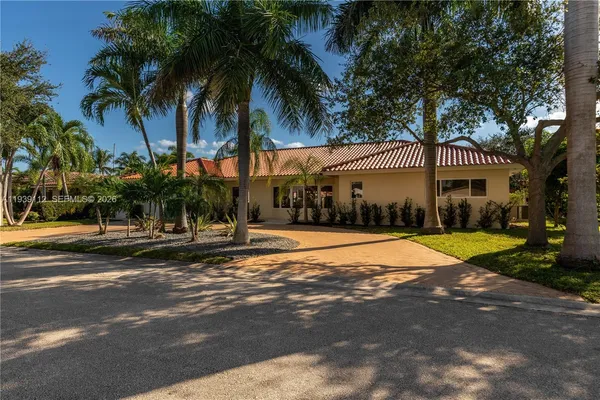 a view of a house with a yard and palm trees