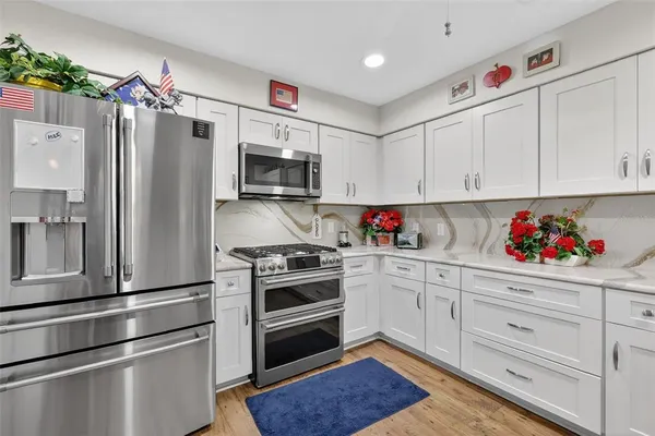 a kitchen with granite countertop a refrigerator stove and white cabinets