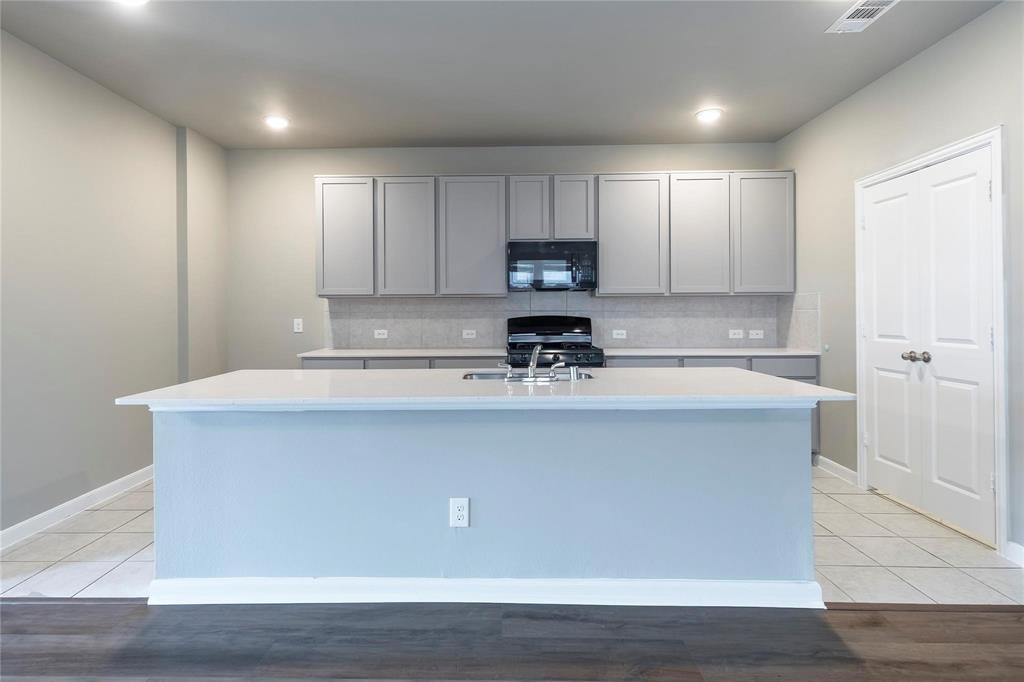 2069 Hartley Drive Forney, TX 75126 - Photo 4 of 27 a view of kitchen with stainless steel appliances granite countertop a stove a sink a refrigerator white cabinets and wooden floor