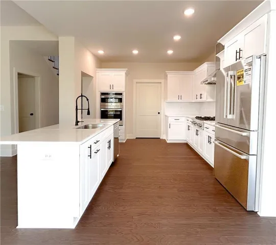 a large kitchen with stainless steel appliances kitchen island granite countertop a stove a sink and a refrigerator