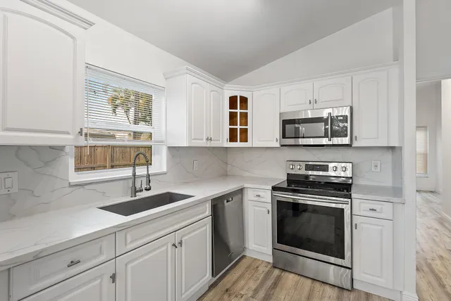 a kitchen with cabinets stainless steel appliances a sink and a window