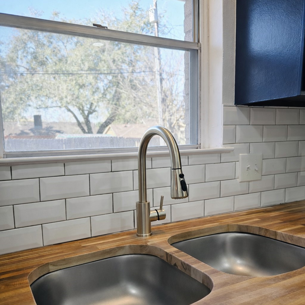 1820 Sunset Avenue Bay City, TX 77414 - Photo 6 of 26 Classic white subway tile backsplash, dual stainless sink and updated hardware, and a view of the fully fenced backyard.