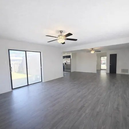 an empty room with wooden floor and a ceiling fan