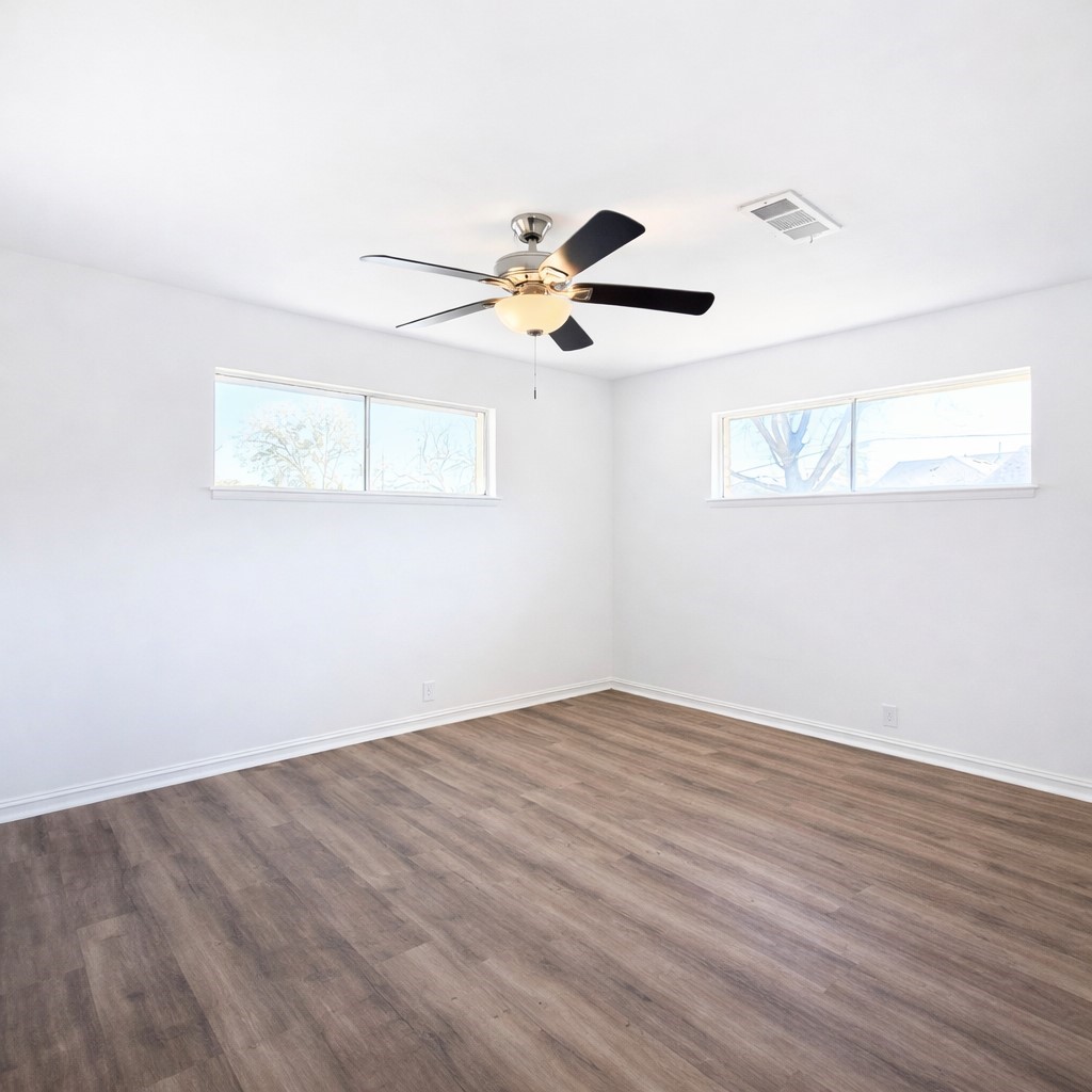 1820 Sunset Avenue Bay City, TX 77414 - Photo 10 of 26 Primary bedroom with laminate flooring, lots of windows, ceiling fan and multiple closets.