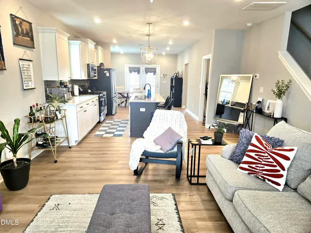 a living room with furniture kitchen view and a chandelier