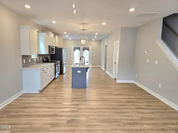 a large kitchen with kitchen island a sink wooden floor and stainless steel appliances