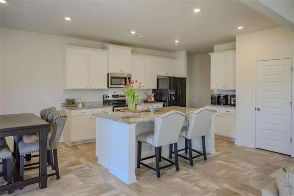 a kitchen with a dining table chairs refrigerator and microwave