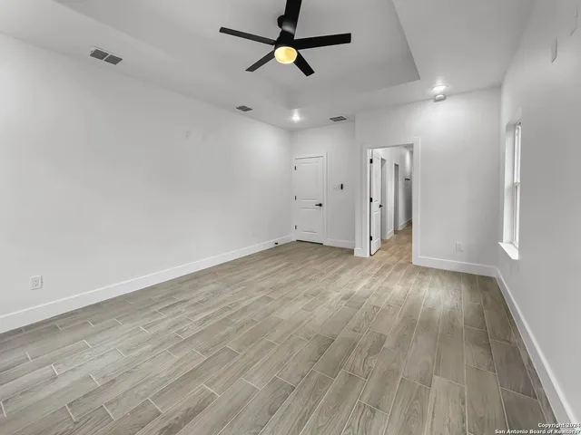 an empty room with wooden floor ceiling fan