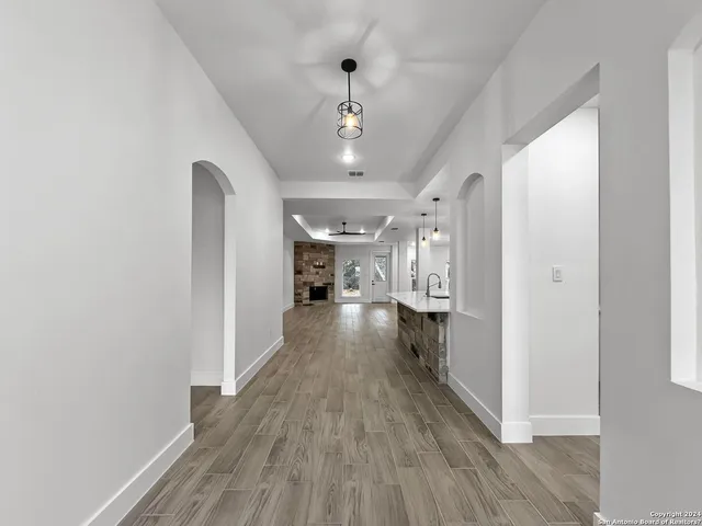 a view of a hallway with wooden floor and chandelier