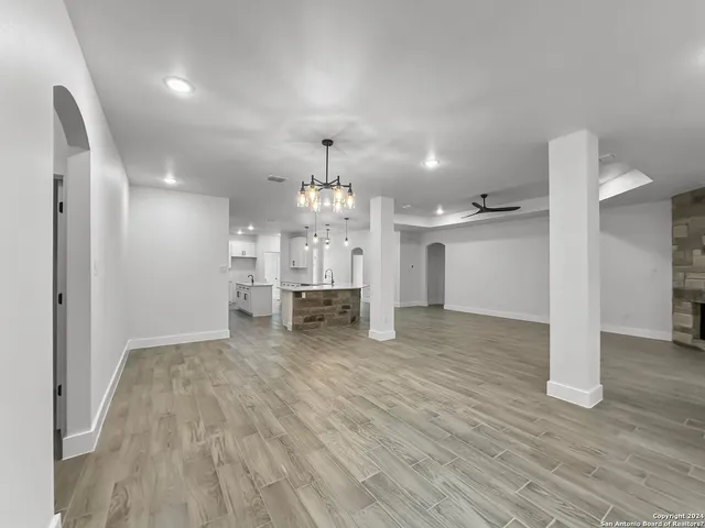 a view of a room with wooden floor kitchen and windows