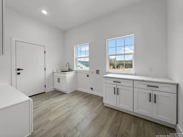 a large white kitchen with stainless steel appliances sink a window and white cabinets