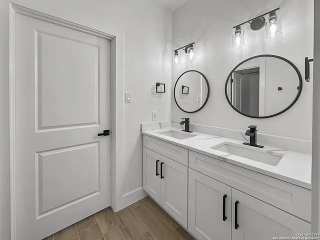 a bathroom with a granite countertop double vanity sink and a mirror